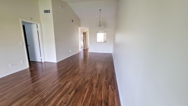 empty room featuring a chandelier, dark hardwood / wood-style flooring, and high vaulted ceiling