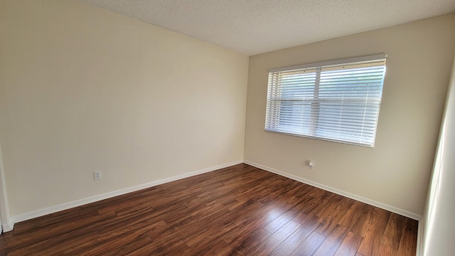 spare room with dark hardwood / wood-style floors and a textured ceiling