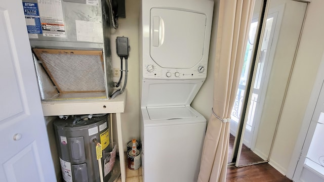 laundry area featuring electric water heater, dark hardwood / wood-style floors, and stacked washer / drying machine