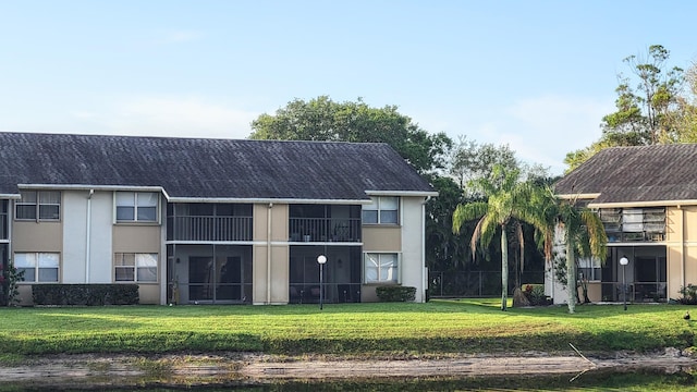 rear view of house with a balcony and a yard