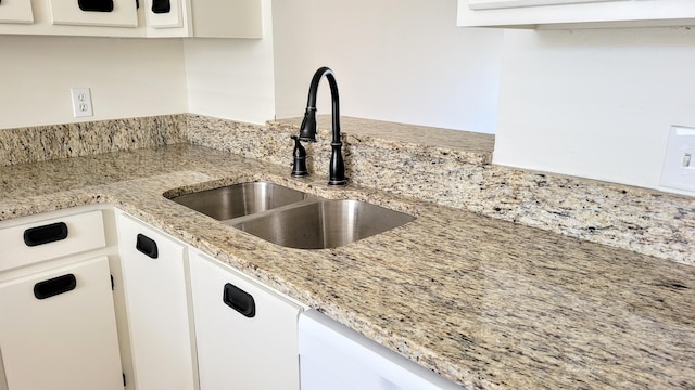 kitchen featuring white cabinets, sink, dishwasher, and light stone counters