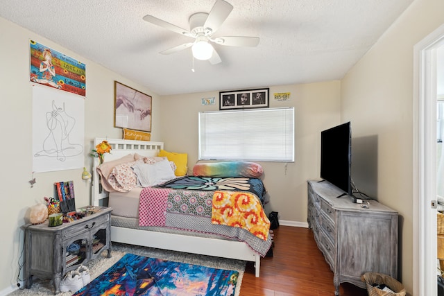 bedroom with a textured ceiling, ceiling fan, dark wood-type flooring, and multiple windows