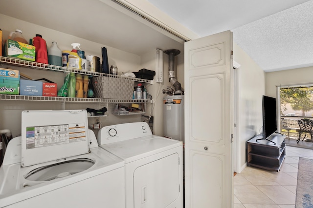 washroom with water heater, a textured ceiling, washer and dryer, and light tile floors