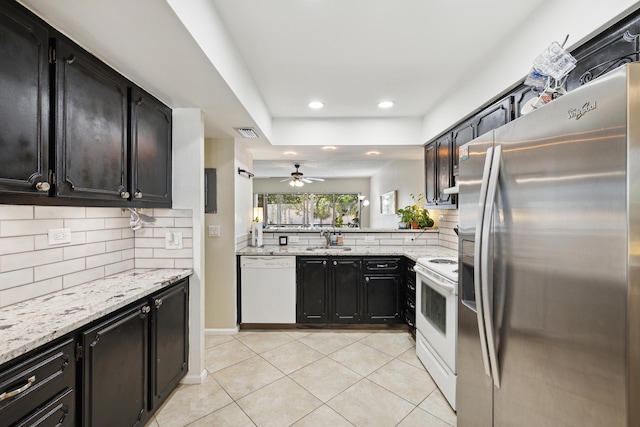 kitchen with white appliances, sink, ceiling fan, light stone counters, and backsplash