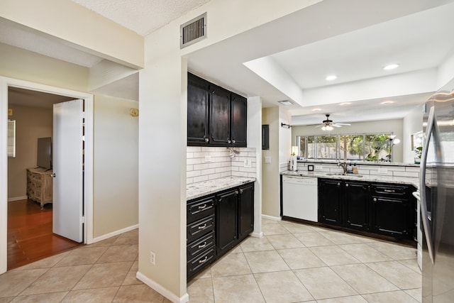 kitchen with ceiling fan, light tile floors, light stone counters, dishwasher, and tasteful backsplash