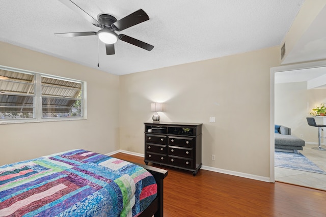 bedroom featuring a textured ceiling, ceiling fan, and dark wood-type flooring