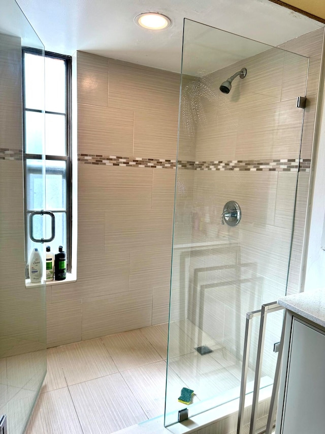 bathroom with vanity, a tile shower, and tile patterned flooring