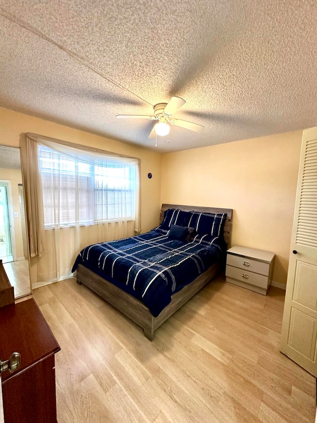 bedroom with a textured ceiling, light wood-type flooring, and ceiling fan