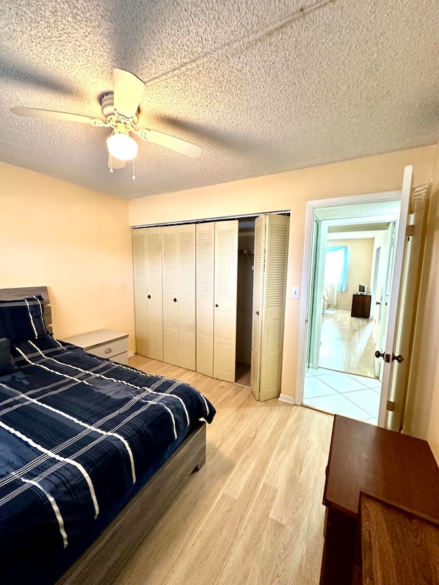 bedroom featuring a closet, a textured ceiling, light wood-type flooring, and ceiling fan