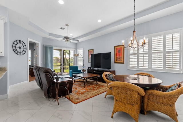 living room featuring ceiling fan with notable chandelier and a raised ceiling