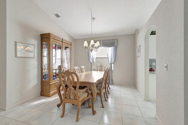 dining space with light tile patterned floors, an inviting chandelier, and vaulted ceiling