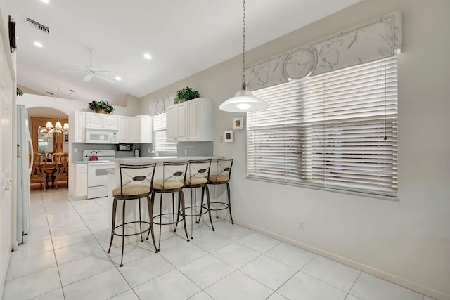 kitchen with ceiling fan with notable chandelier, lofted ceiling, white cabinets, kitchen peninsula, and white appliances