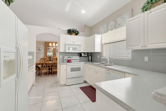 kitchen featuring vaulted ceiling, sink, light tile patterned floors, white cabinetry, and white appliances