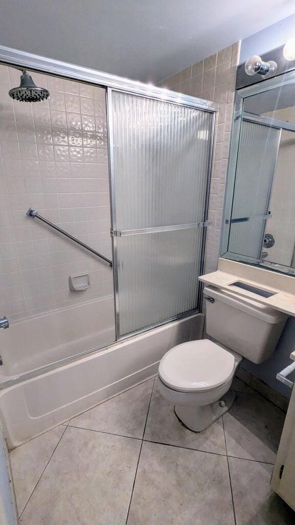 bathroom with tile patterned flooring, toilet, and shower / bath combination with glass door