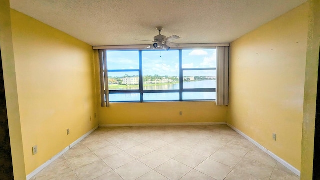 unfurnished room featuring a textured ceiling, a water view, and ceiling fan