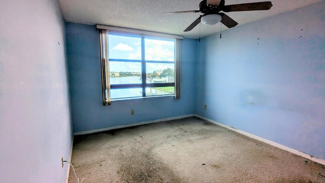 unfurnished room with carpet flooring, ceiling fan, a water view, and a textured ceiling