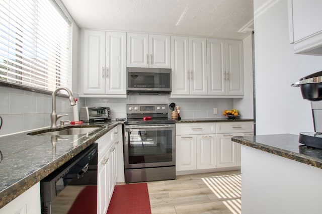 kitchen featuring white cabinetry, appliances with stainless steel finishes, sink, a textured ceiling, and tasteful backsplash