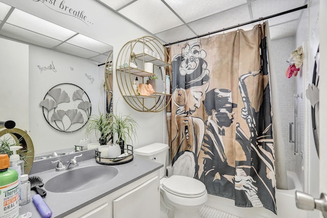 full bathroom featuring vanity, shower / bath combo, tile floors, toilet, and a drop ceiling