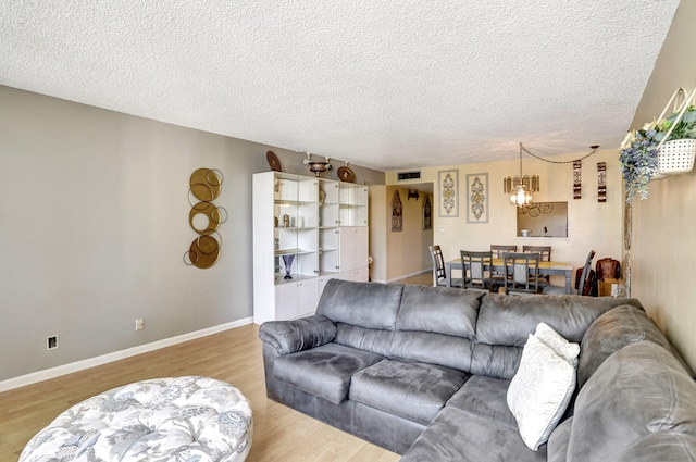 living room featuring light hardwood / wood-style floors, a notable chandelier, and a textured ceiling