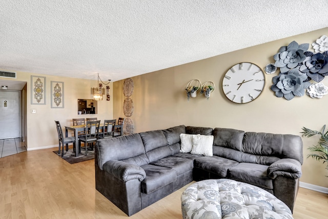 living room featuring a textured ceiling, a chandelier, and light hardwood / wood-style floors