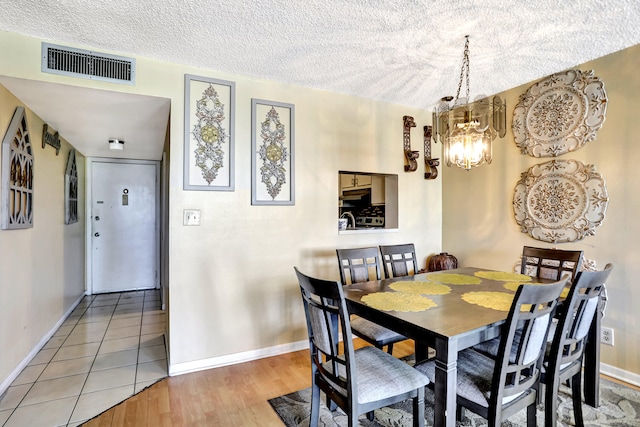 tiled dining room with an inviting chandelier and a textured ceiling