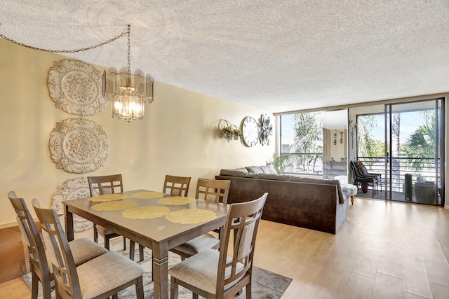 dining area with floor to ceiling windows, light hardwood / wood-style floors, a textured ceiling, and a notable chandelier