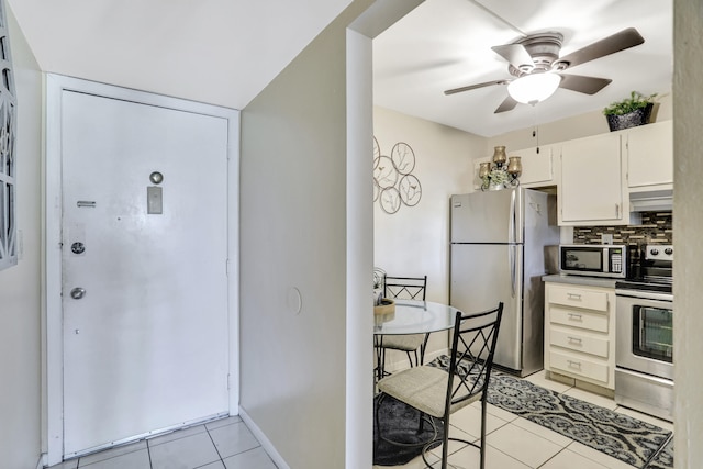 kitchen featuring white cabinetry, backsplash, ceiling fan, stainless steel appliances, and light tile floors