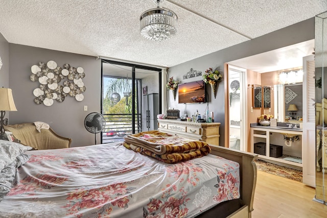 bedroom with an inviting chandelier, a textured ceiling, access to exterior, and light wood-type flooring