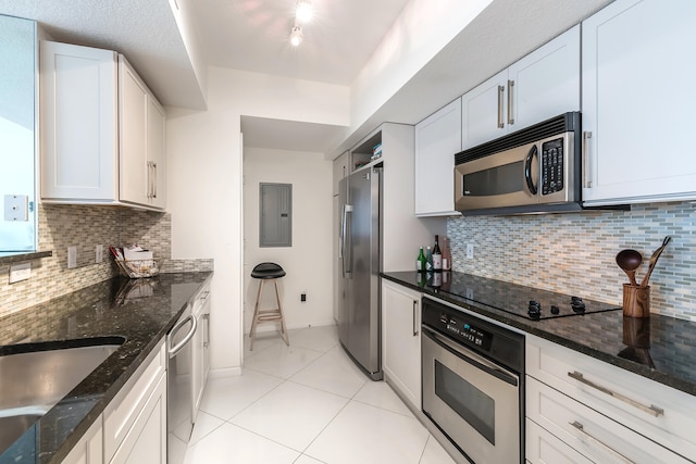 kitchen with dark stone counters, decorative backsplash, white cabinets, and stainless steel appliances