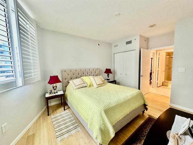 bedroom with light hardwood / wood-style floors, a textured ceiling, and a closet