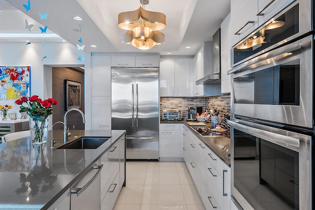 kitchen with white cabinetry, sink, wall chimney exhaust hood, stainless steel appliances, and tasteful backsplash