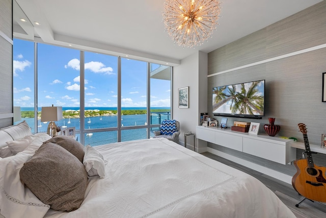 bedroom featuring an inviting chandelier, expansive windows, hardwood / wood-style flooring, and a water view