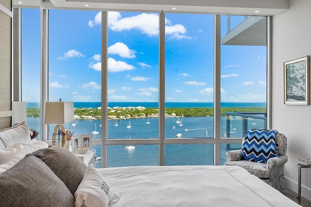 bedroom featuring a water view and a wall of windows