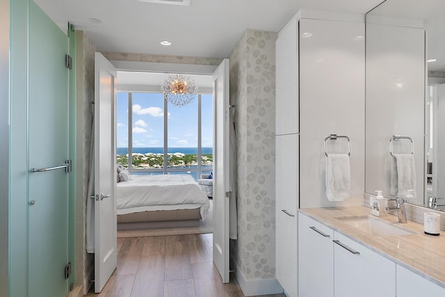 bathroom featuring an inviting chandelier, vanity, hardwood / wood-style flooring, and a water view