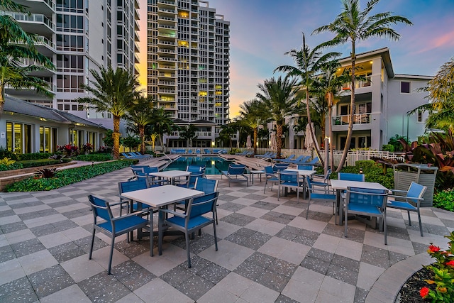 patio terrace at dusk featuring a balcony and a community pool