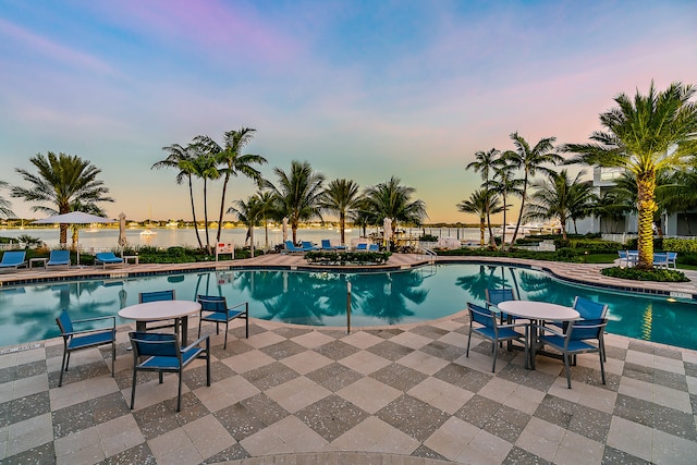 pool at dusk with a patio area