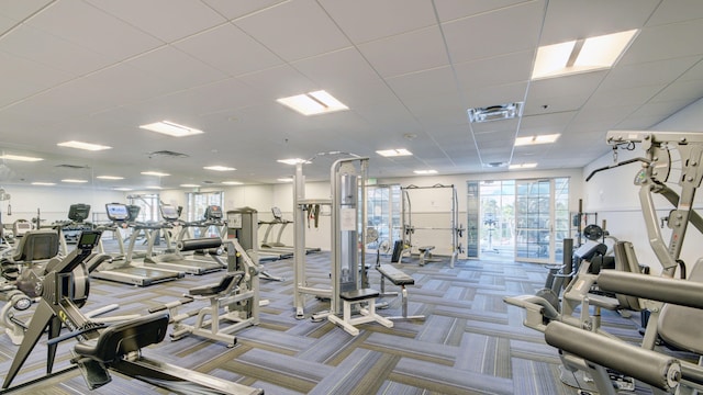 gym with a paneled ceiling and light carpet