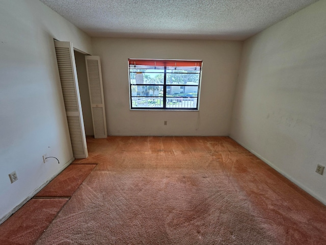 spare room with light carpet and a textured ceiling