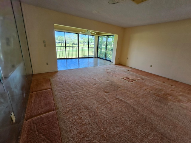 unfurnished room with carpet, ceiling fan, and a textured ceiling