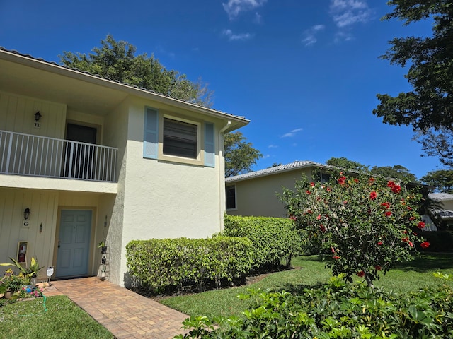 view of side of home with a yard and a balcony