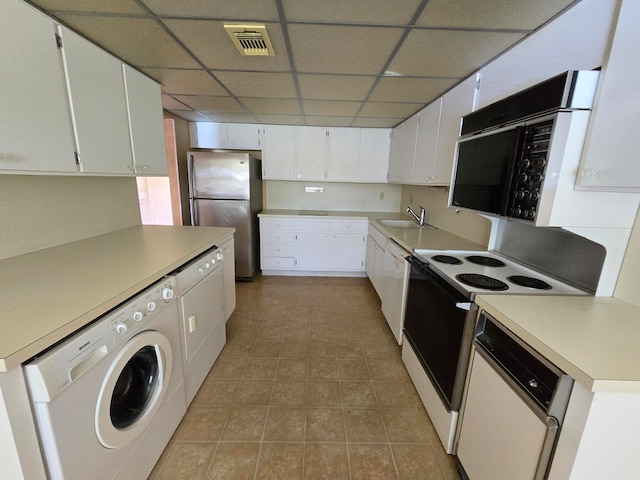 kitchen with a drop ceiling, white appliances, tile floors, and white cabinets