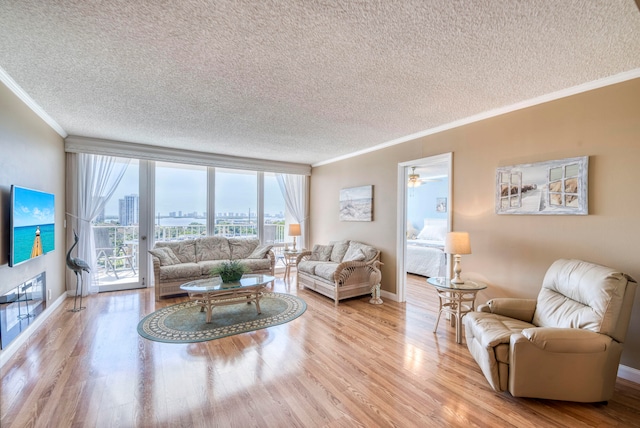 living room featuring ceiling fan, light hardwood / wood-style flooring, a textured ceiling, and crown molding