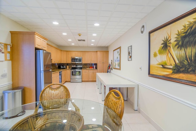 kitchen featuring light tile floors, appliances with stainless steel finishes, and backsplash