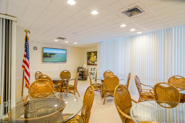 tiled dining space featuring a drop ceiling