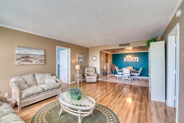 living room featuring ornamental molding, a textured ceiling, and light hardwood / wood-style flooring