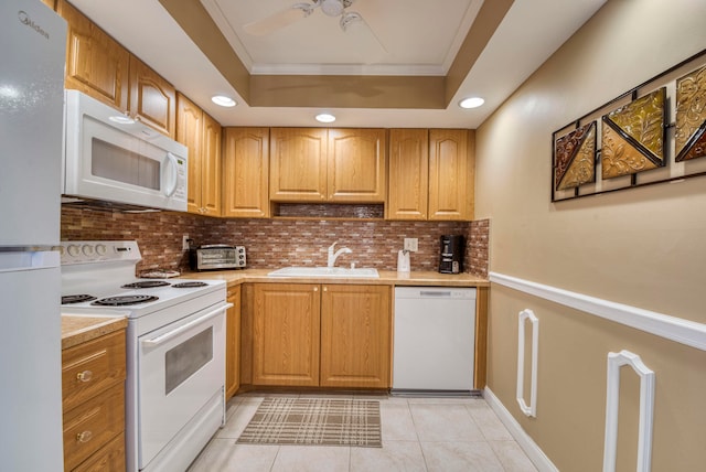 kitchen featuring white appliances, a tray ceiling, ceiling fan, and sink