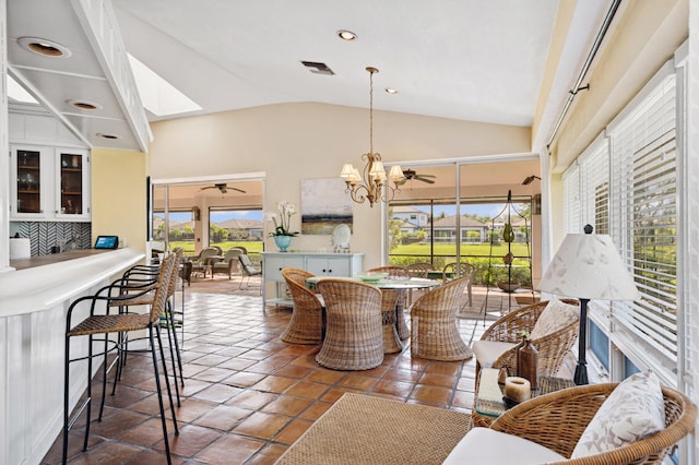 tiled dining space with plenty of natural light, high vaulted ceiling, and ceiling fan with notable chandelier