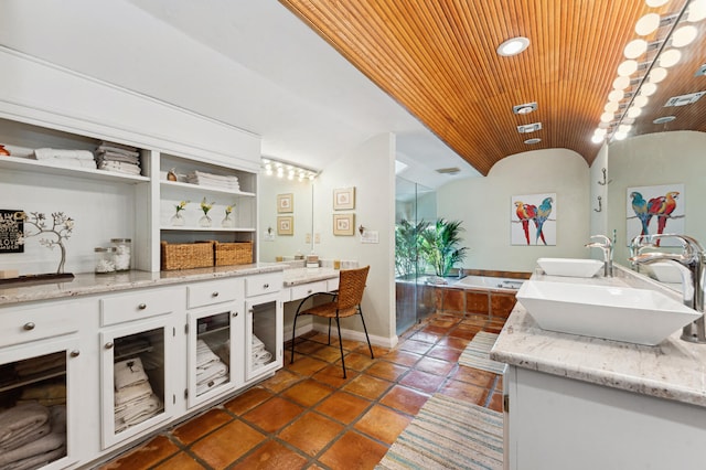 kitchen with light stone counters, dark tile floors, white cabinetry, and sink