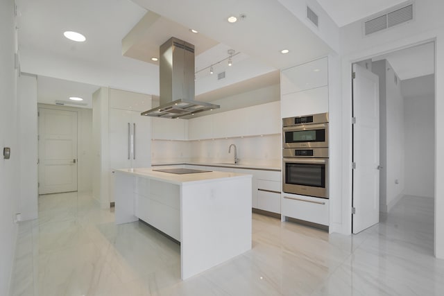 kitchen featuring sink, a kitchen island, stainless steel double oven, island range hood, and white cabinetry