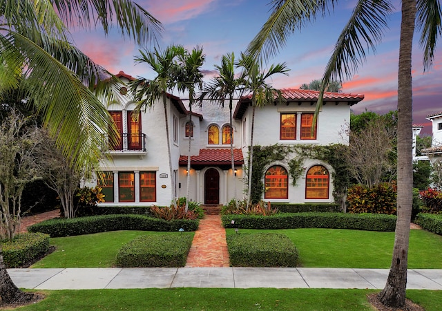 mediterranean / spanish-style house with a balcony and a lawn